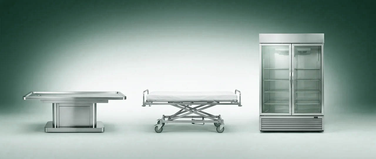 Embalming table, mortuary cot, and refrigeration unit — core prep-room equipment.